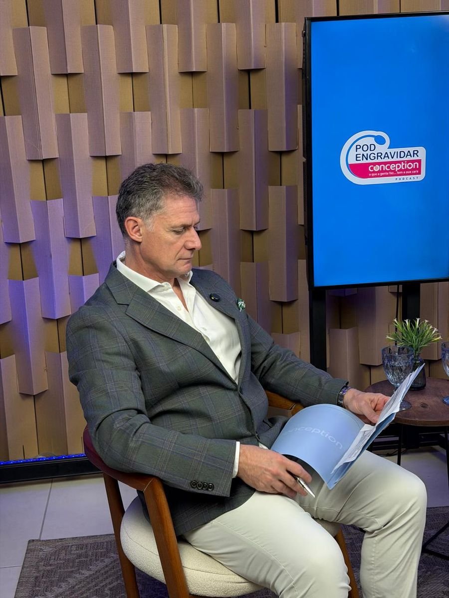Dr. Fábio ao lado da tela com o logo do PodEngravidar